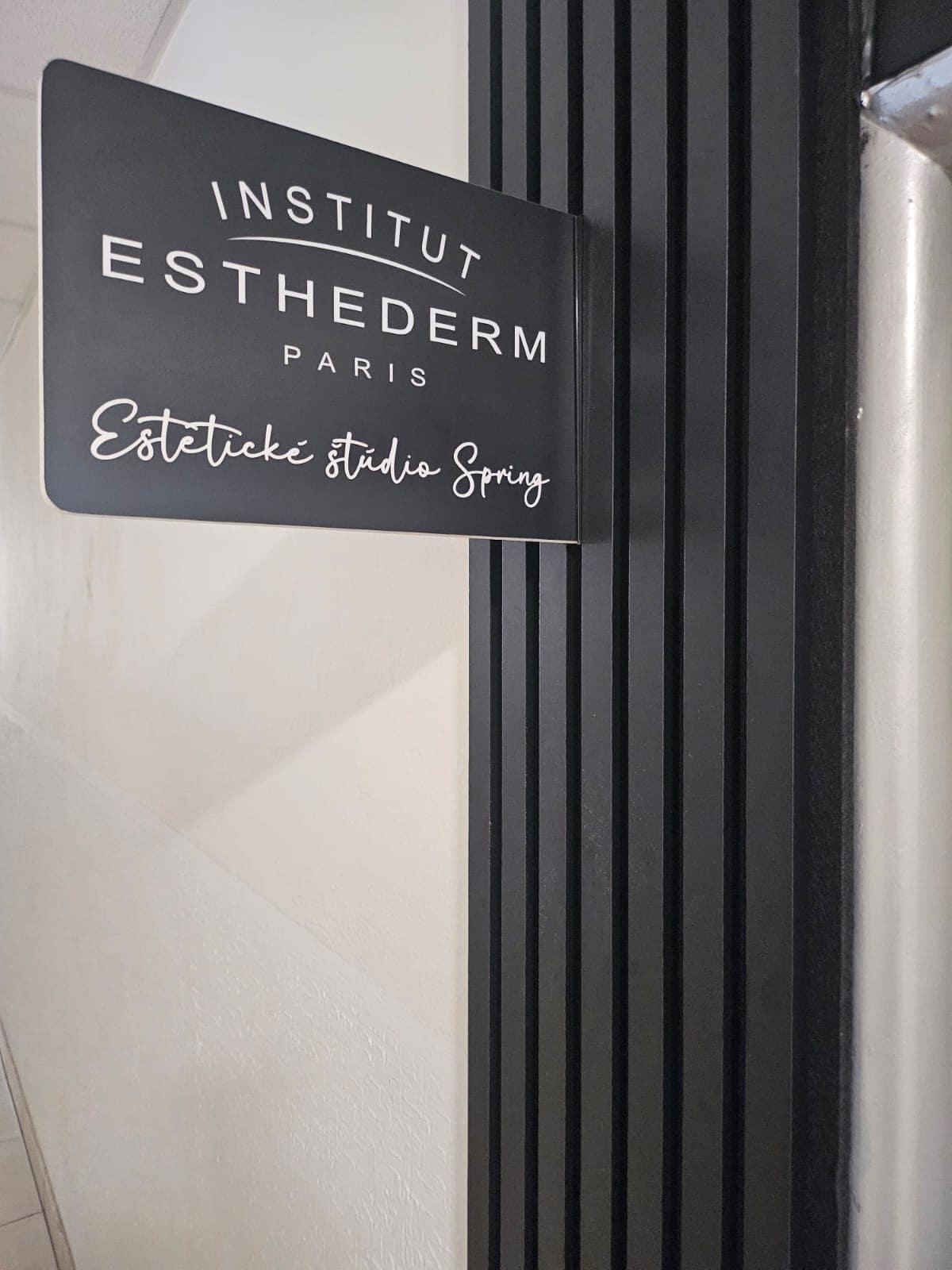 Vstupná tabuľa Estetického štúdia Spring s logom Institut Esthederm Paris na čiernej lamelovej stene v schodisku.
